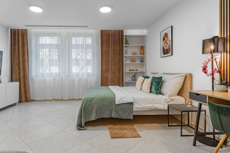 I Luxusný byt v historickom centre Bratislavy - Spálňa 2-izbového bytu s veľkou posteľou, pestrými doplnkami a nábytkom v svetlých tónoch.