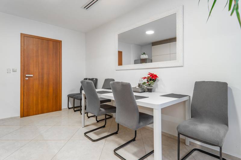 I Luxusný byt v historickom centre Bratislavy - Jedálenský stôl so sivými stoličkami a dekoráciami v interiéri 2-izbového bytu.