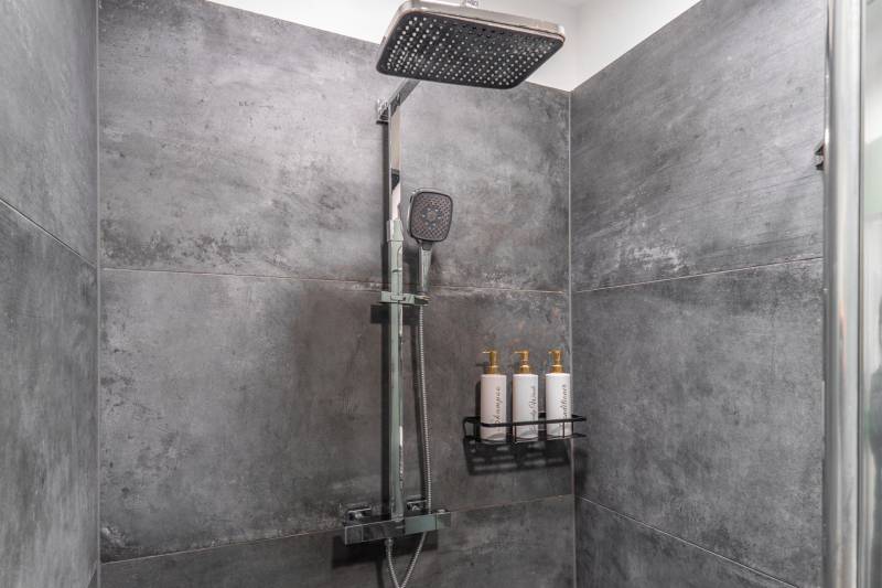 I Luxusný byt v historickom centre Bratislavy - Sprchový kút s tmavými obkladmi a nástennými dávkovačmi v 2-izbovom byte.
