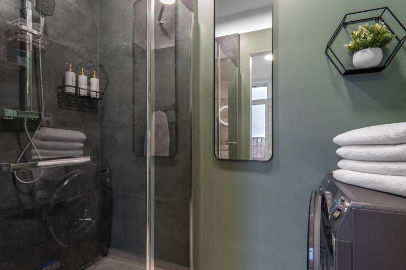 I Luxusný byt v historickom centre Bratislavy - Kúpeľňa v 2-izbovom byte s preskleným sprchovým kútom, uterákmi a dekoráciami.