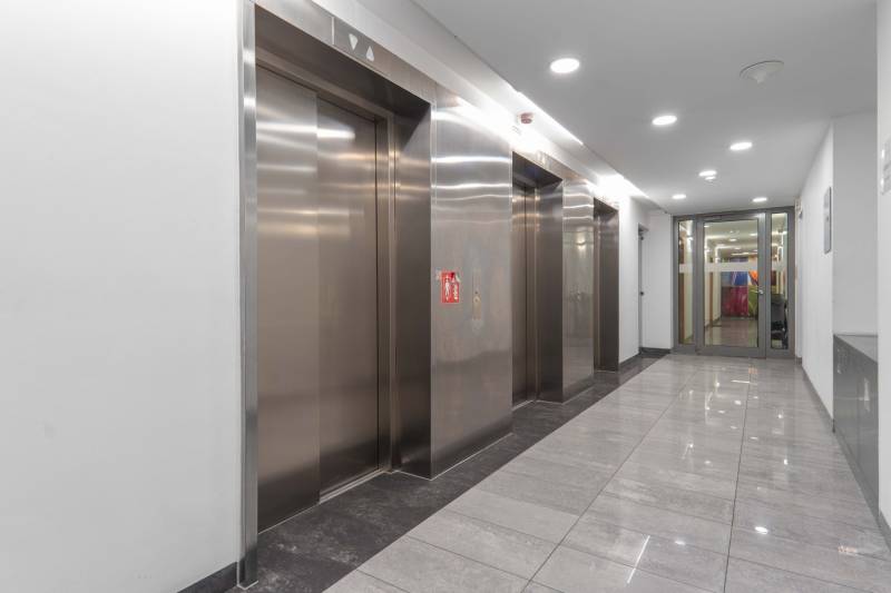 I na predaj 2i byt v komplexe Tri Veže na Bajkalskej - Chodba s nerezovými výťahmi a lesklou kamennou podlahou v administratívnej budove.