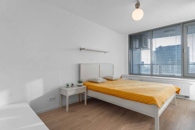 I na predaj 2i byt v komplexe Tri Veže na Bajkalskej - Svetlá spálňa v 2-izbovom byte s posteľou a podlahou s dreveným dekorom.