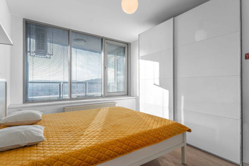 I na predaj 2i byt v komplexe Tri Veže na Bajkalskej - Spálňa s veľkými oknami, žltým prehozom a vstavanou skriňou v 2-izbovom byte.