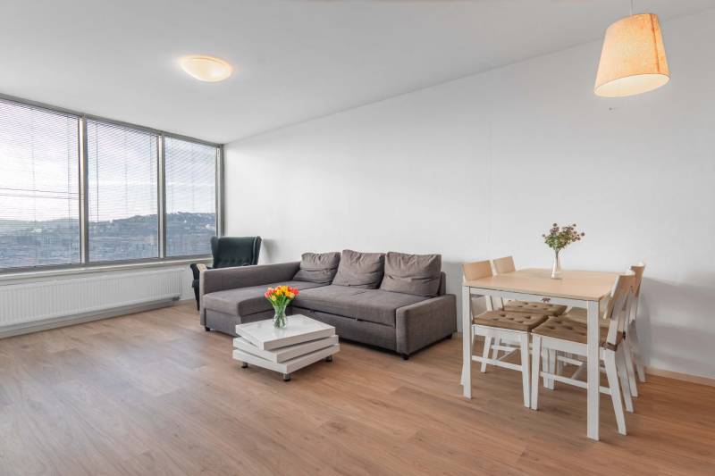 I na predaj 2i byt v komplexe Tri Veže na Bajkalskej - Obývacia izba 2-izbového bytu s podlahou s dreveným dekorom, pohovkou a jedálenským stolom.