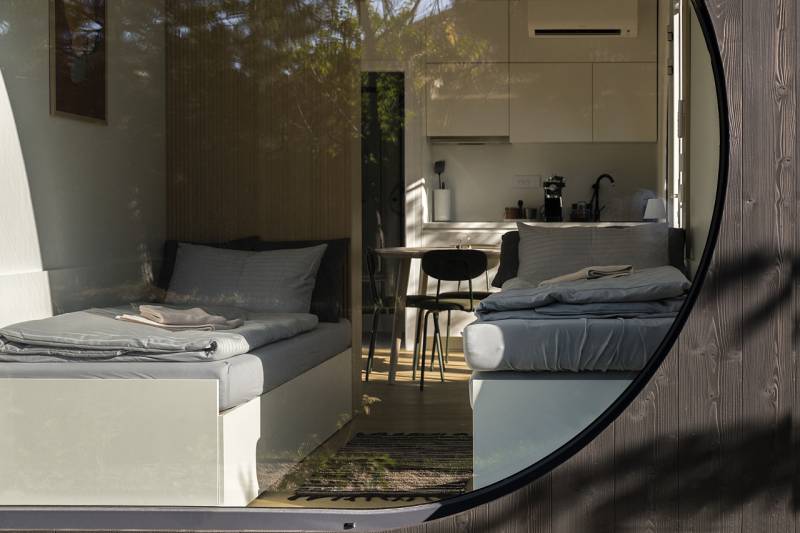 I Predaj Ecocapsule – autonómne ekologické bývanie - Interiér s dvoma posteľami, kuchyňou a podlahou s dreveným dekorom. Zvláštne nehnuteľnosti.