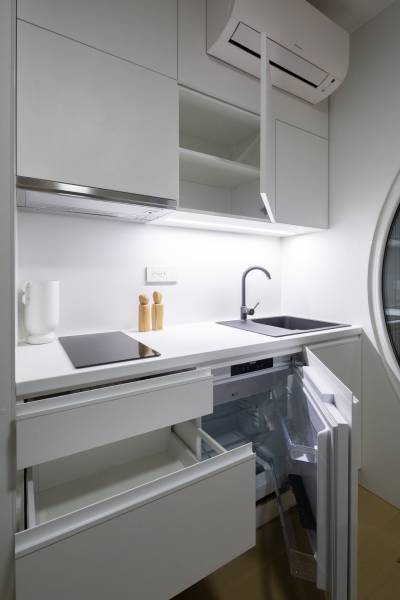 I Predaj Ecocapsule – autonómne ekologické bývanie - Kompaktná kuchynská linka v bielej farbe so spotrebičmi a úložným priestorom.