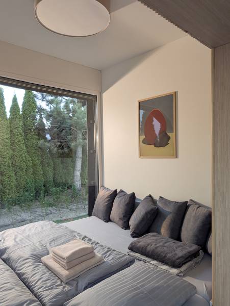 I Predaj Ecocapsule – autonómne ekologické bývanie - Zvláštne nehnuteľnosti s pohľadom na záhradu, posteľ s dekoračnými vankúšmi a obrazom.