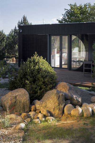 I Predaj Ecocapsule – autonómne ekologické bývanie - Skalka s kameňmi pred zvláštnou nehnuteľnosťou v Bratislave, obklopené zeleňou a stromami.