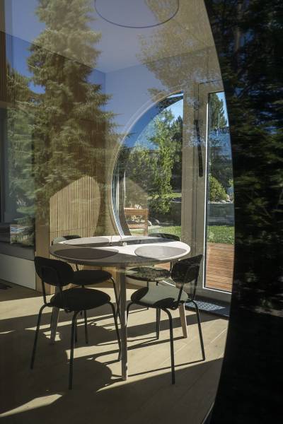 I Predaj Ecocapsule – autonómne ekologické bývanie - Interiér so stolom, stoličkami a podlahou s dreveným dekorom cez okno do záhrady.