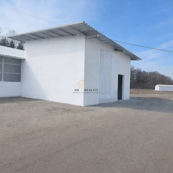 Predaj, výrobný a veľkoobchodný areál v okrese Veľký Krtíš - Výrobné priestory vo Veľkom Krtíši s bielou fasádou a veľkou bránou.