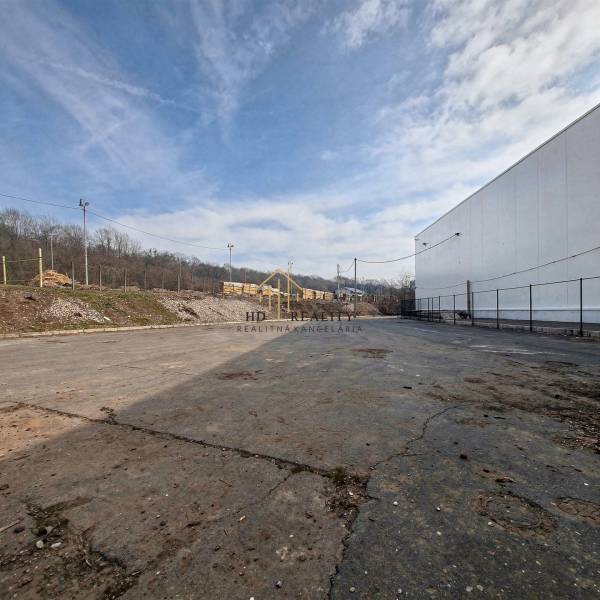 Predaj, výrobný a veľkoobchodný areál v okrese Veľký Krtíš - Výrobné priestory vo Veľkom Krtíši s asfaltovou plochou a oplotením, priemyselná oblasť.