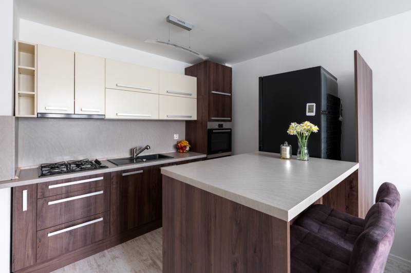 Prenájom Štýlový 2-iz bový byt pri OC Central BEZ PROVÍZIE!!!!  - Kuchyňa v 2-izbovom byte s podlahou s dreveným dekorom, barovým pultom a moderným vybavením.