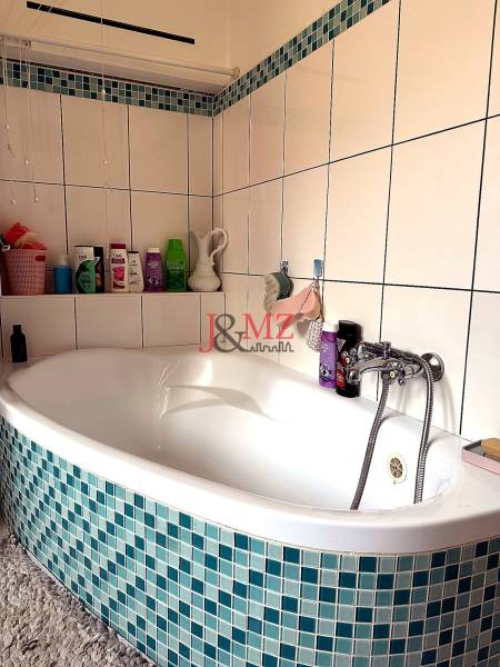 2 izb. byt CENTRUM Levice  - Kúpeľňa s rohovou vaňou a modro-bielym obkladom v 2-izbovom byte.