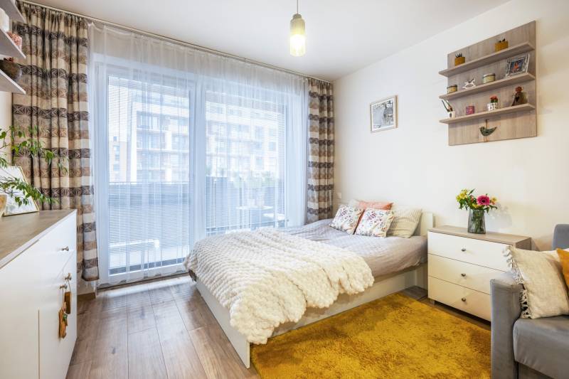 Prenájom 1-izbového bytu, Béžová, Béžová, Petržalka - REZERVOVANÉ - Svetlý 1-izbový byt s posteľou, kobercom a podlahou s dreveným dekorom.