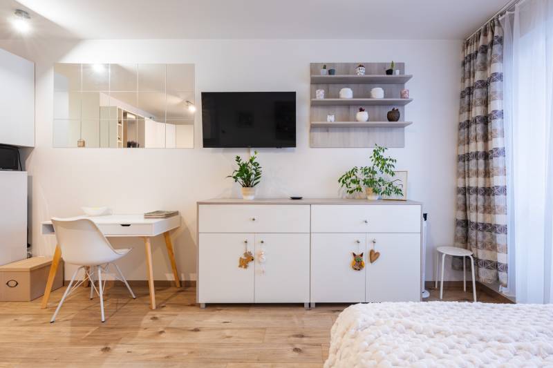 Prenájom 1-izbového bytu, Béžová, Béžová, Petržalka - REZERVOVANÉ - Interiér 1-izbového bytu s bielym nábytkom a podlahou s dreveným dekorom.