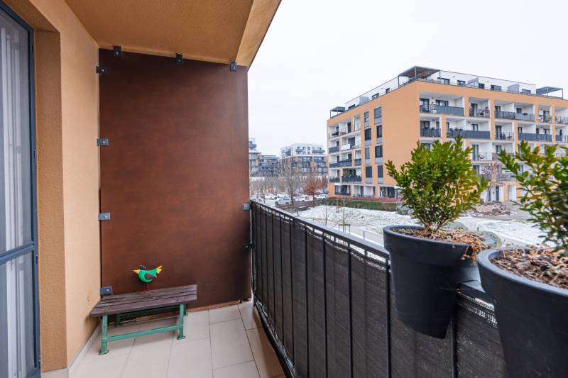 Prenájom 1-izbového bytu, Béžová, Béžová, Petržalka - REZERVOVANÉ - Balkón 1-izbového bytu na Béžovej ulici v Bratislave - Petržalke so zeleňou a lavičkou.