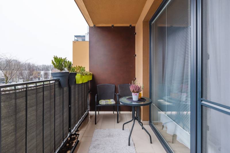 Prenájom 1-izbového bytu, Béžová, Béžová, Petržalka - REZERVOVANÉ - Balkón v 1-izbovom byte na Béžovej ulici v Bratislave - Petržalke s rastlinami a nábytkom.