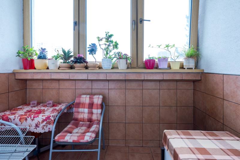 Predaj 4-izbového bytu, Vyšehradská, Vyšehradská, Petržalka - Zariadený 4-izbový byt s kvetmi na parapete a stolíkom s kobercom na balkóne.