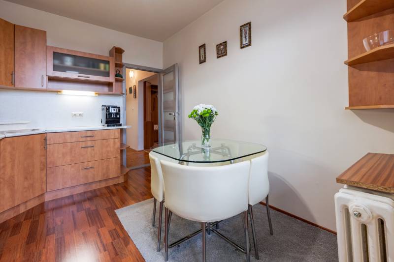 Predaj 4-izbového bytu, Vyšehradská, Vyšehradská, Petržalka - Kuchyňa v 4-izbovom byte so skleneným stolom, podlaha s dreveným dekorom, biele steny.