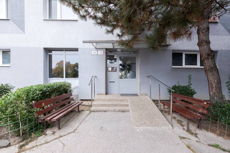 Predaj 4-izbového bytu, Vyšehradská, Vyšehradská, Petržalka - Vchod do budovy na Vyšehradskej ulici v Bratislave - Petržalke s lavičkami a zeleňou.