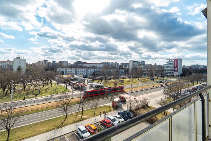 Komfortný 1,5-izbový byt s balkónom v Ružinove na predaj - Výhľad na rušnú ulicu v Bratislave - Ružinov, Súmračná, s električkou a parkom.