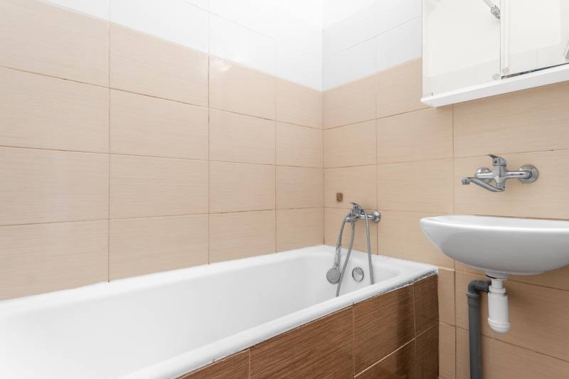 Komfortný 1,5-izbový byt s balkónom v Ružinove na predaj - Kúpeľňa s vaňou a umývadlom v 1-izbovom byte, béžová dlažba.