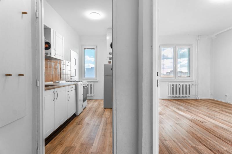 Komfortný 1,5-izbový byt s balkónom v Ružinove na predaj - Svetlá kuchyňa a obývacia izba s podlahou s dreveným dekorom v 1-izbovom byte.