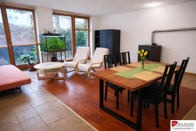 Prenájom 3-izbového bytu so záhradkou, 81m2, Pezinok-Centrum. - Obývacia izba v 3-izbovom byte s podlahou s dreveným dekorom, jedálenským stolom a akváriom.