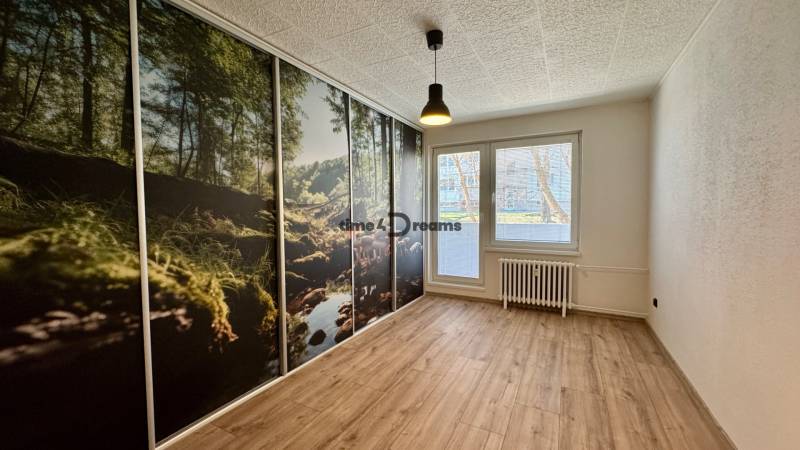 NA PRENÁJOM veľký 3 izbový byt na Čermáni NITRA - Izba v 3-izbovom byte s veľkoplošnou tapetou lesa a podlahou s dreveným dekorom.