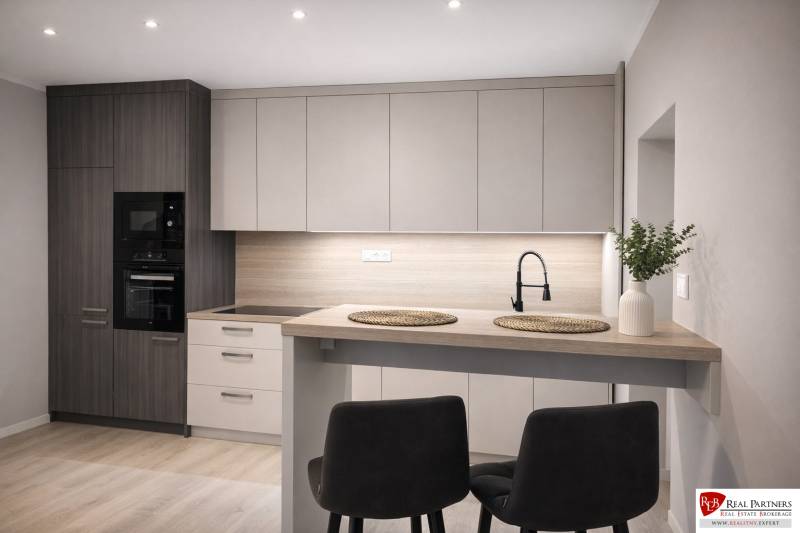 Prenájom 2-izbový byt s loggiou, 54m2, Bratislava-Petržalka - Kuchyňa v 2-izbovom byte s podlahou s dreveným dekorom, modernou linkou a jedálenským stolom.