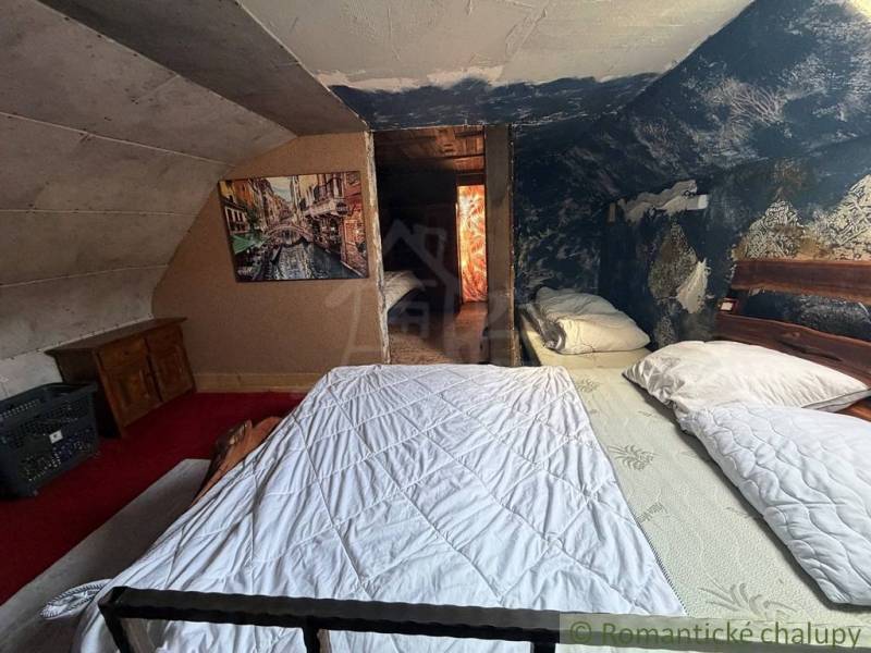 Štýlová chalupa v horskej dedinke Ratkovské Bystré - Podkrovná spálňa v rodinnom dome s obrazom a modrou stenou plnou vzorov.