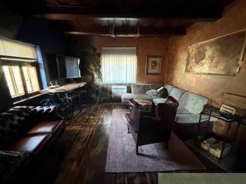 Štýlová chalupa v horskej dedinke Ratkovské Bystré - Obývačka v rodinnom dome s podlahou s dreveným dekorom a pohodlným sedením.