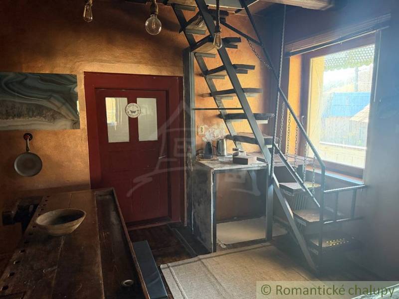 Štýlová chalupa v horskej dedinke Ratkovské Bystré - Interiér rodinného domu s kovovým schodiskom a dreveným stolom, svetlé steny.