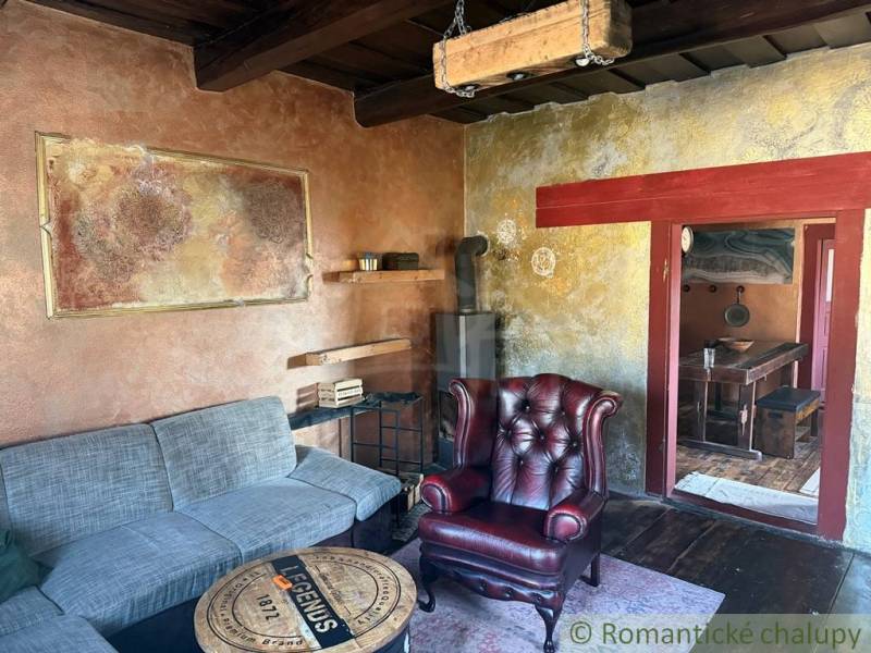 Štýlová chalupa v horskej dedinke Ratkovské Bystré - Obývacia izba v rodinnom dome s koženým kreslom a kachľovou pecou.