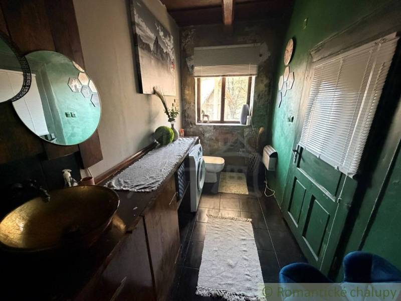 Štýlová chalupa v horskej dedinke Ratkovské Bystré - Kúpeľňa v rodinnom dome s tmavými stenami, toaletou a pračkou.