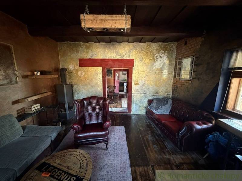 Štýlová chalupa v horskej dedinke Ratkovské Bystré - Rustikálna obývacia izba v rodinnom dome s koženými kreslami a podlahou s dreveným dekorom.