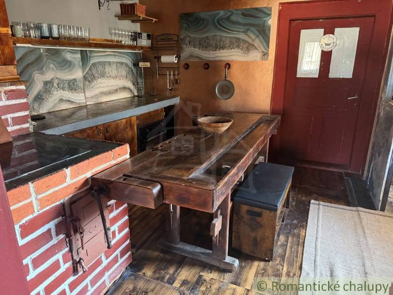 Štýlová chalupa v horskej dedinke Ratkovské Bystré - Rustikálna kuchyňa v rodinnom dome s tehlovými detailmi a podlahou s dreveným dekorom.