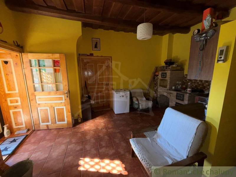 Exkluzívne: Pekná chalupa v obci Lipovec - Izba v rodinnom dome s tehlovou podlahou, dreveným stropom a žltými stenami.