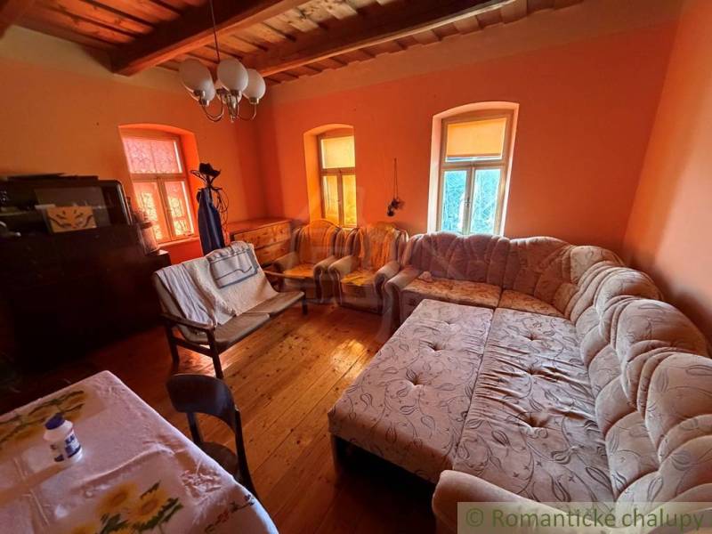 Exkluzívne: Pekná chalupa v obci Lipovec - Obývacia izba v rodinnom dome s veľkým gaučom a podlahou s dreveným dekorom.