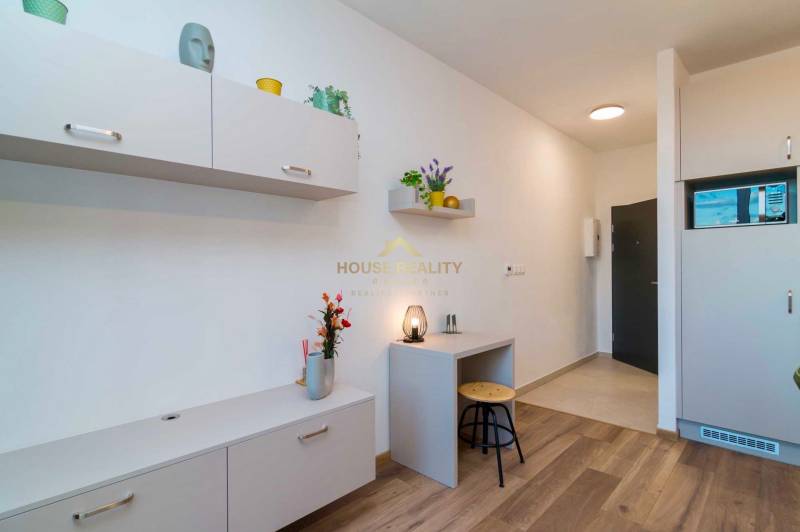 Novostavba 1 izbový byt, Bernolákovská ulica, Ivanka pri Dunaji - Interiér 1-izbového bytu so svetlým nábytkom a podlahou s dreveným dekorom.