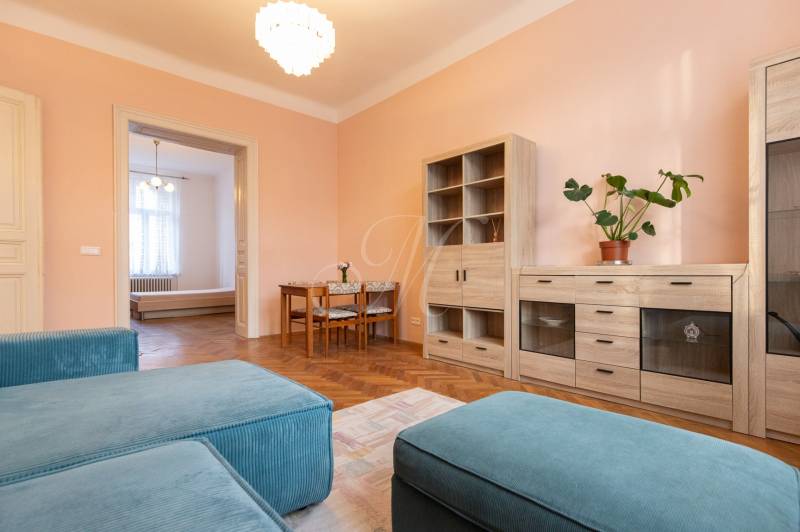 3-izbový byt s vysokými stropmi, Staré Mesto - Obývacia izba v 3-izbovom byte s podlahou s dreveným dekorom a pastelovými stenami.