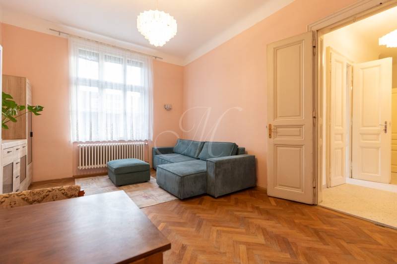 3-izbový byt s vysokými stropmi, Staré Mesto - Svetlá obývačka s pohovkou, lustrom a podlahou s dreveným dekorom v 3-izbovom byte.