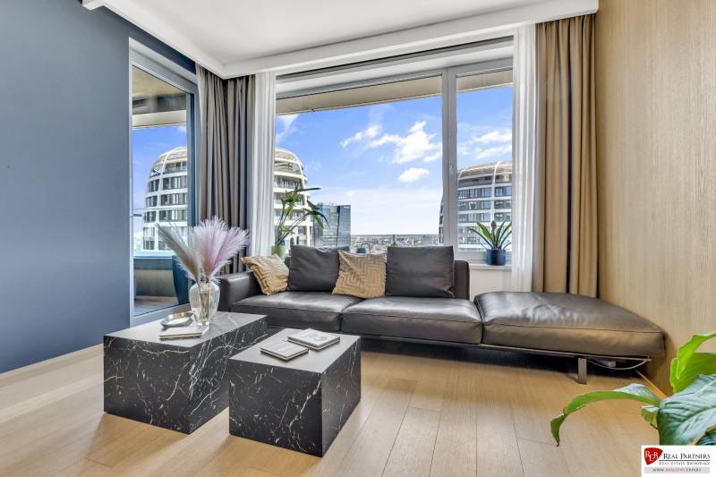 Predaj luxusný 2-izbový byt, 52 m2, Továrenská ul, SKY PARK - Obývacia izba v 2-izbovom byte s čiernou pohovkou, kávovým stolíkom a výhľadom na mesto.