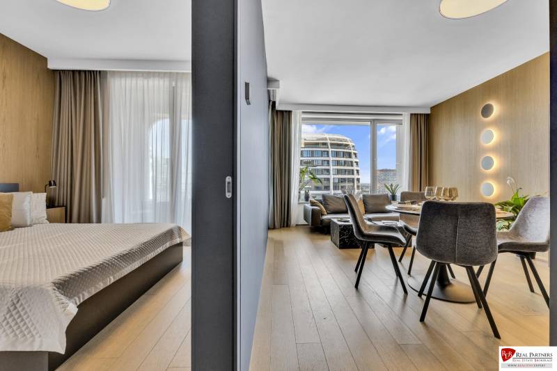 Predaj luxusný 2-izbový byt, 52 m2, Továrenská ul, SKY PARK - Interiér 2-izbového bytu s podlahou s dreveným dekorom a výhľadom na mesto.