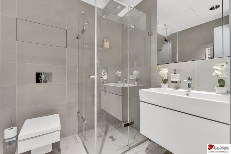 Predaj luxusný 2-izbový byt, 52 m2, Továrenská ul, SKY PARK - Kúpeľňa v 2-izbovom byte s preskleným sprchovým kútom a svetlými obkladmi.