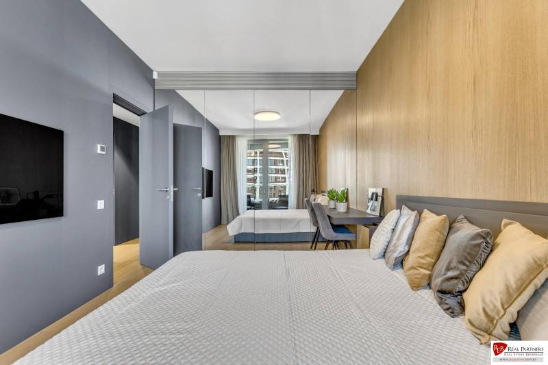 Predaj luxusný 2-izbový byt, 52 m2, Továrenská ul, SKY PARK - Spálňa v 2-izbovom byte s podlahou s dreveným dekorom a zrkadlovou stenou.