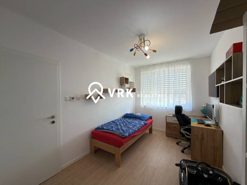 3-izbový byt s garážovým státím – Košice Západ, ul. Topoľčianska - Detská izba v 3-izbovom byte s podlahou s dreveným dekorom, písacím stolom, posteľou.