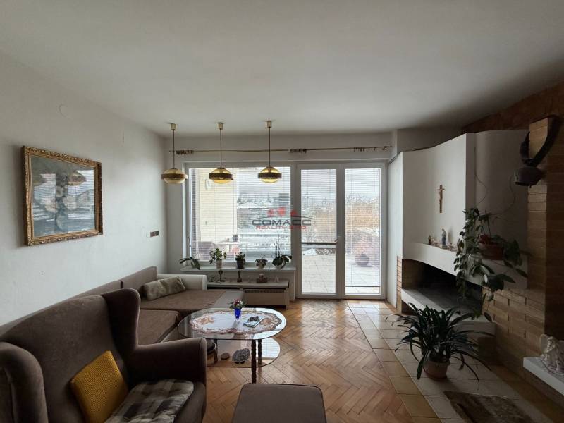 Exk. viacgeneračný RD vo Veľkom Orvišti pri Piešťanoch REZERVOVANÝ - Obývačka v rodinnom dome s krbom, sedačkou a podlahou s dreveným dekorom.