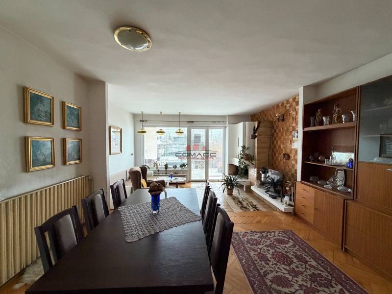 Exk. viacgeneračný RD vo Veľkom Orvišti pri Piešťanoch REZERVOVANÝ - Obývačka v rodinnom dome s podlahou s dreveným dekorom, jedálenským stolom a krbom.