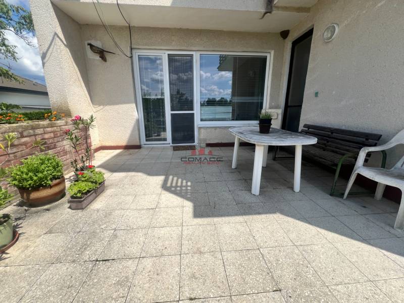 Exk. viacgeneračný RD vo Veľkom Orvišti pri Piešťanoch REZERVOVANÝ - Terasa rodinného domu v Tálovej ulici vo Veľkom Orvišti s plastovým stolom a kvetmi.